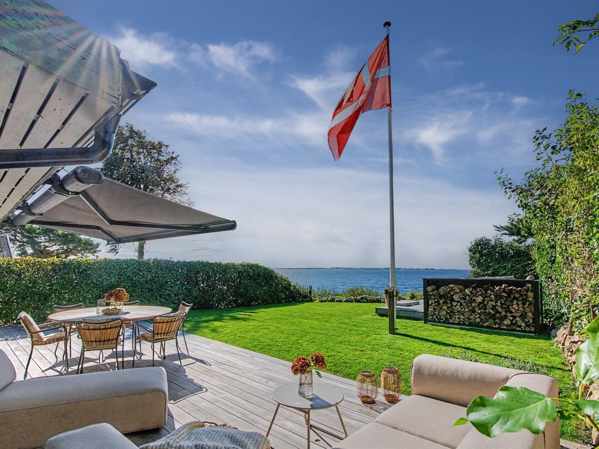 Une terrasse dotée de mobilier d’extérieur, d’un drapeau et offrant une vue sur la mer.