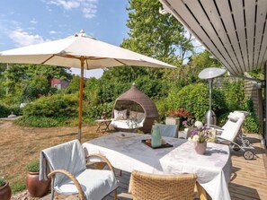 Relax in style with a dining table set amidst lush greenery and a cozy seating area.