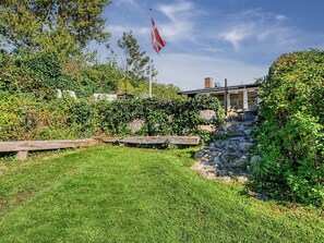 A well-maintained garden with a grassy lawn, stone walls, and a flagpole.