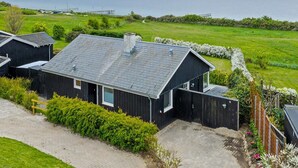 A modern black house with a sloped roof, a chimney, and a view of a large body of water. - "Annalia" - 50m from the sea by Interhome (Faaborg)