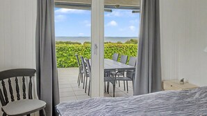 A room with a bed, a chair, a table, and a view of a patio with chairs and a table. - "Annalia" - 50m from the sea by Interhome (Faaborg)