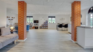 A spacious living area with a sofa, TV, and a dining table with chairs.
