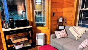 A cozy cabin interior with a sofa, a small table, and a kitchenette area.