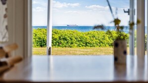 Vista da janela com um navio na água, e vegetação ao primeiro plano.
