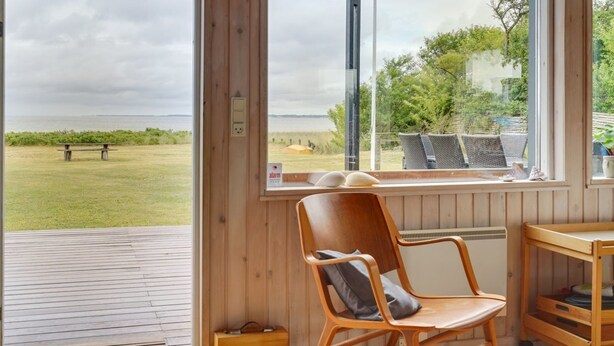 A wooden-framed room with a view of the sea, a chair, and a small table. - "Sigurd" - 20m from the sea by Interhome (Middelfart)