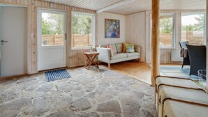 A room with wooden walls and a stone floor, a sofa, a small table, and a painting on the wall. - "Sigurd" - 20m from the sea by Interhome (Middelfart)
