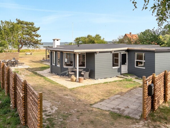 A modern single-story house with a covered patio, a small deck, and a view of the ocean.