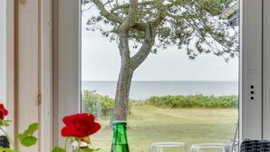 A view from a room with a glass door to a grassy area and a tree, with a bottle and glasses on the table. - "Sigurd" - 20m from the sea by Interhome (Middelfart)