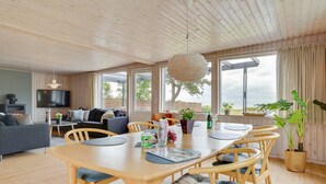 A modern living room with a wooden ceiling, a large TV, a sofa, a dining table with chairs, and a view of the outdoors. - "Sigurd" - 20m from the sea by Interhome (Middelfart)