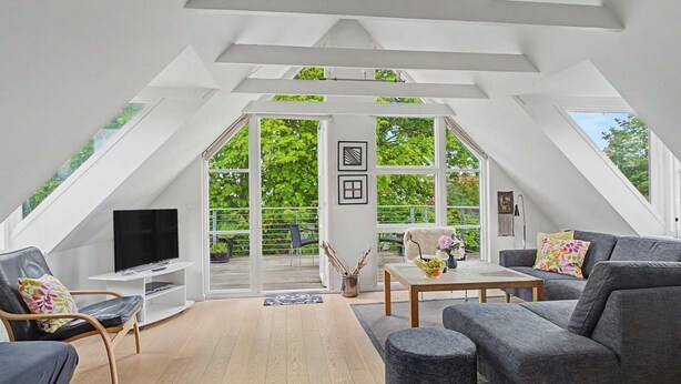 A spacious attic room with a TV, seating, and large windows. - "Gullan" - 75m from the sea by Interhome (Middelfart)