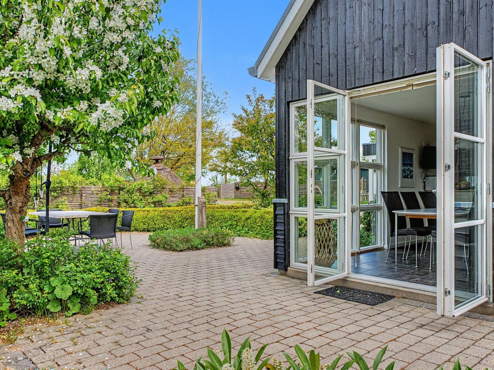 A modern building with large glass doors, outdoor seating, and a well-maintained garden.