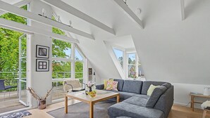 A spacious loft with a large gray sofa, a wooden coffee table, and a view of greenery outside. - "Gullan" - 75m from the sea by Interhome (Middelfart)