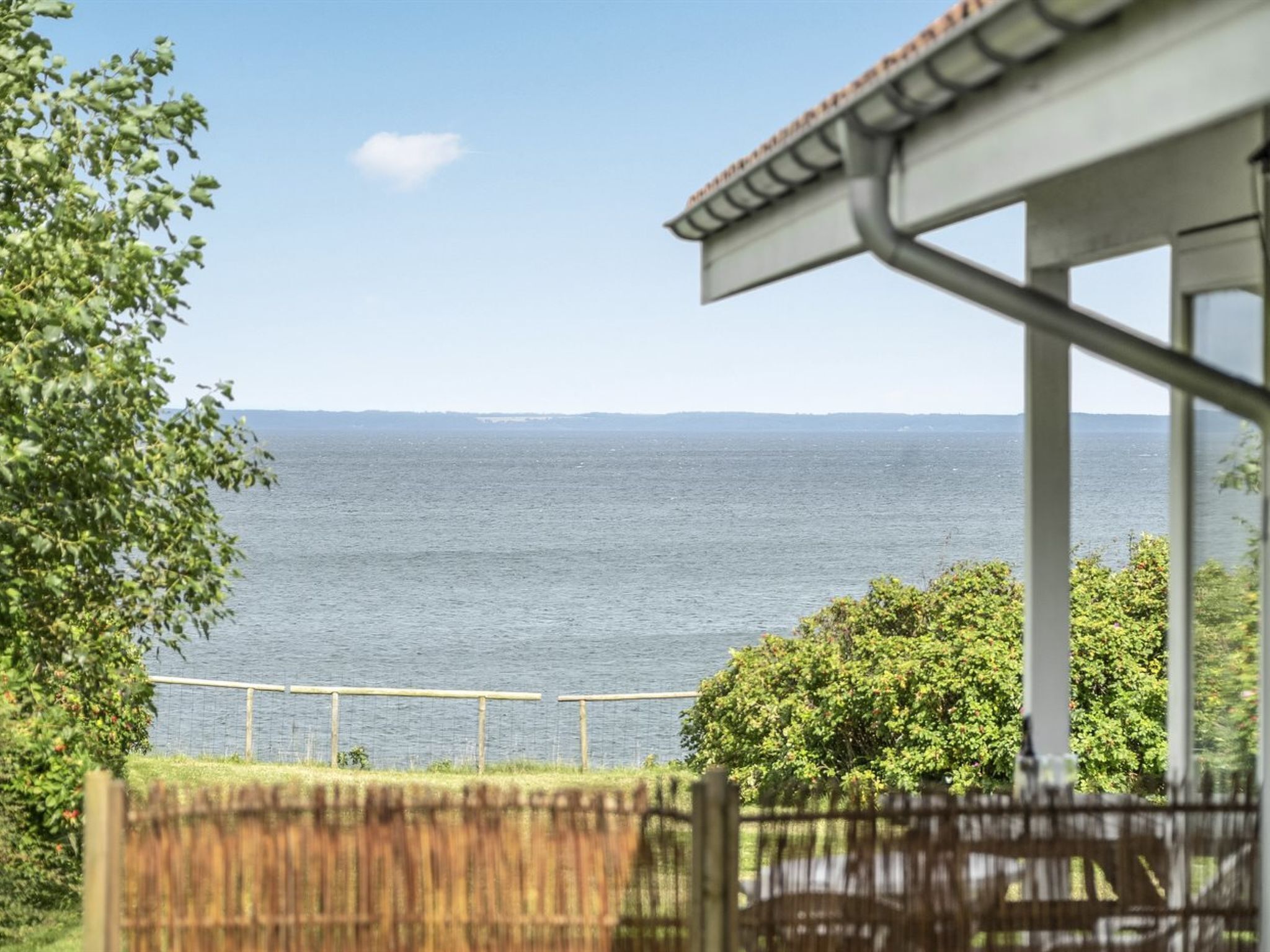 Une vue sur la côte depuis un espace extérieur abrité, doté d’une balustrade, qui donne sur la mer.