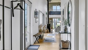 En moderne gang med trægulv, bænk, knagerække og et konsolbord med en plante.
