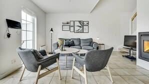 Ett modernt vardagsrum med en soffa, två fåtöljer, ett soffbord, en öppen spis, en tv och konstverk på väggen.
