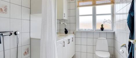 A bathroom with a shower, toilet, and window with a view.