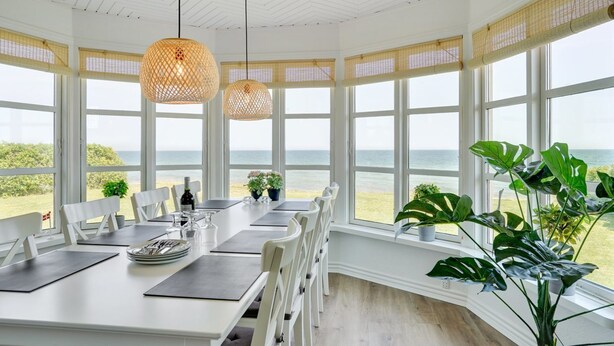 A dining area with a view of the sea, large windows, and hanging wicker lamps. - "Hwitserk" - 5m from the sea by Interhome (Otterup)