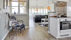 A modern kitchen with a Bosch oven, a dining area with a black sofa, and a view of the sea through large windows. - "Hwitserk" - 5m from the sea by Interhome (Otterup)