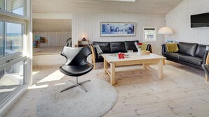 A modern living room with a black leather sofa, a wooden coffee table, and a black chair. There are skylights above the sofa and a painting on the wall. - "Diertje" - 10m from the sea by Interhome (Otterup)