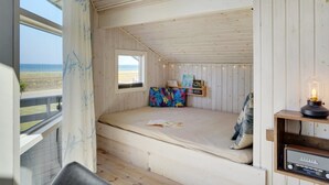 A small, cozy bedroom with a single bed, a window with a view of the beach, a shelf with books and a vintage radio. - "Diertje" - 10m from the sea by Interhome (Otterup)