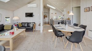 A modern interior with a dining area, a living room with a sofa and TV, and a kitchen in the background. - "Diertje" - 10m from the sea by Interhome (Otterup)