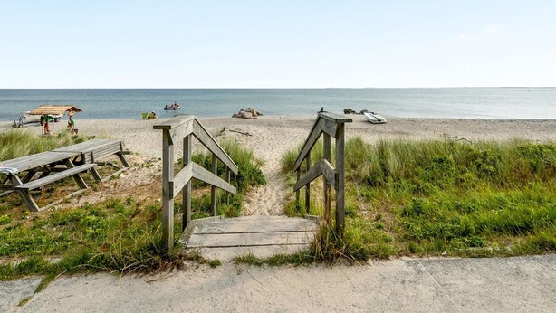 Een houten trap die naar een zandstrand leidt, met een helder uitzicht op de oceaan.