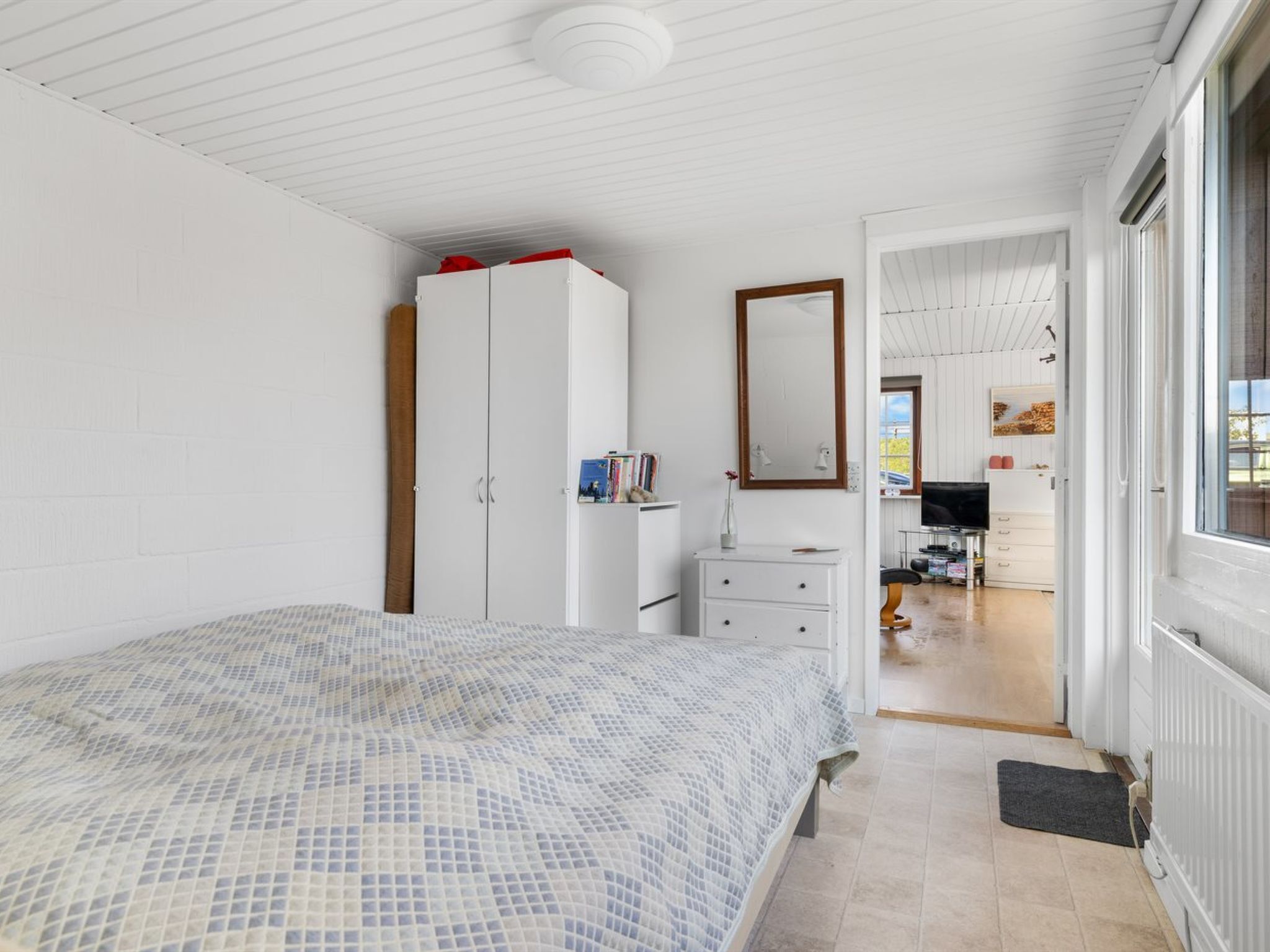 A bedroom with a bed, a wardrobe, a dresser, and a mirror.