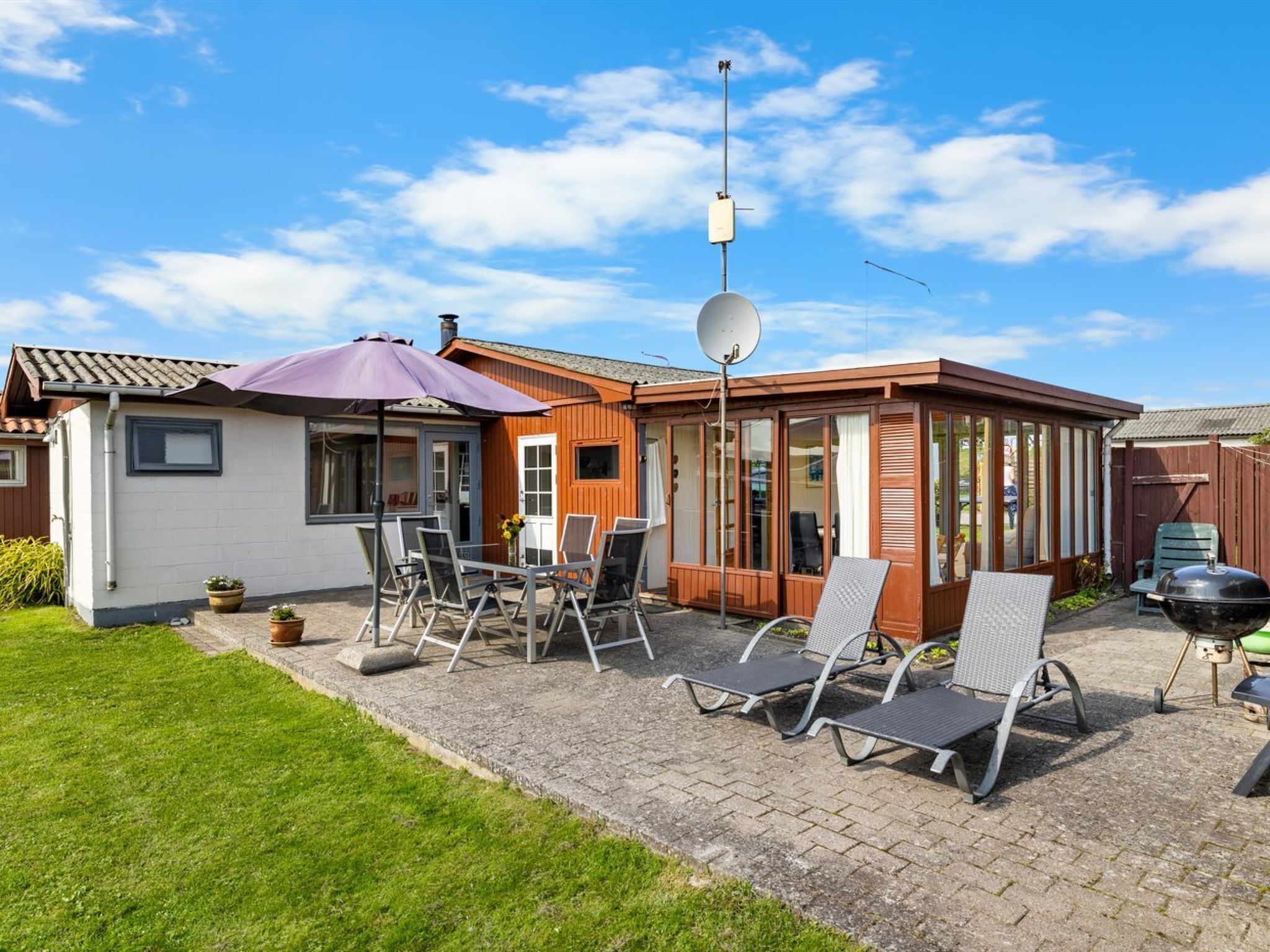 A house with a patio area featuring outdoor furniture and a barbecue.