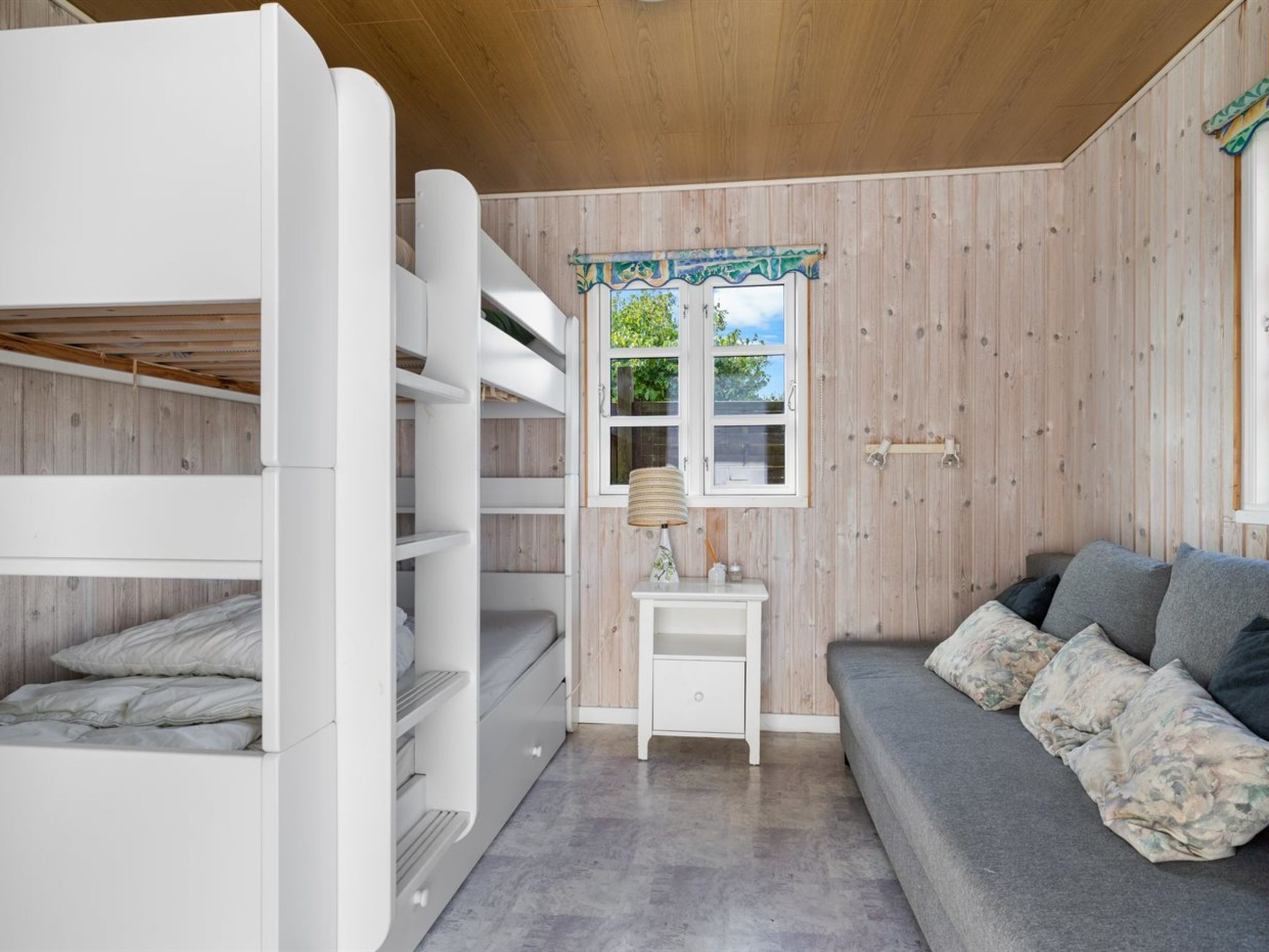 A bunk bed room with a small table and a sofa.