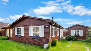 Een houten huis met twee ramen, een schoorsteen en een tuin met een pad.