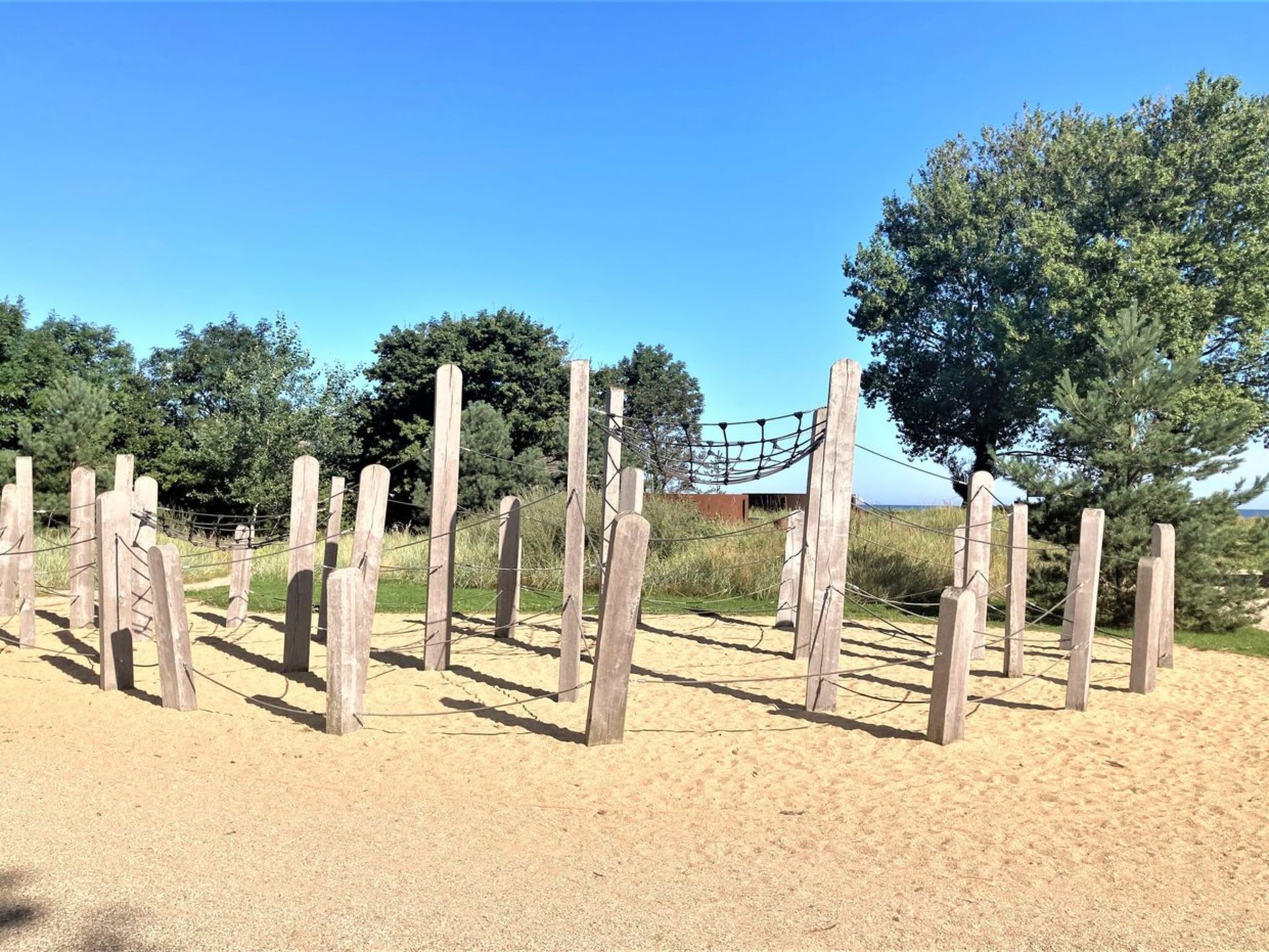 Una playa arenosa con postes de madera y una estructura de red.