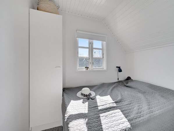 Un dormitorio con cama, ventana, lámpara y armario.