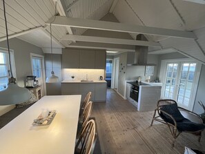 Een koelkast, een vaatwasser, kookgerei, borden en bestek