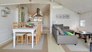 A spacious living area with a dining table, wooden chairs, a grey sofa, and a coffee table.