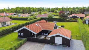 A residential area with houses featuring red-tiled roofs, a gravel driveway, and well-maintained lawns.