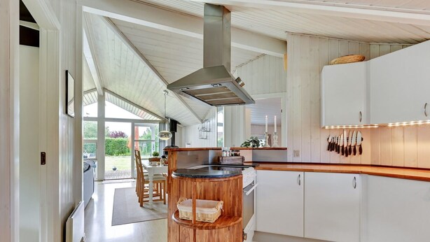 A modern kitchen with a central island, white cabinetry, and a large window providing natural light.