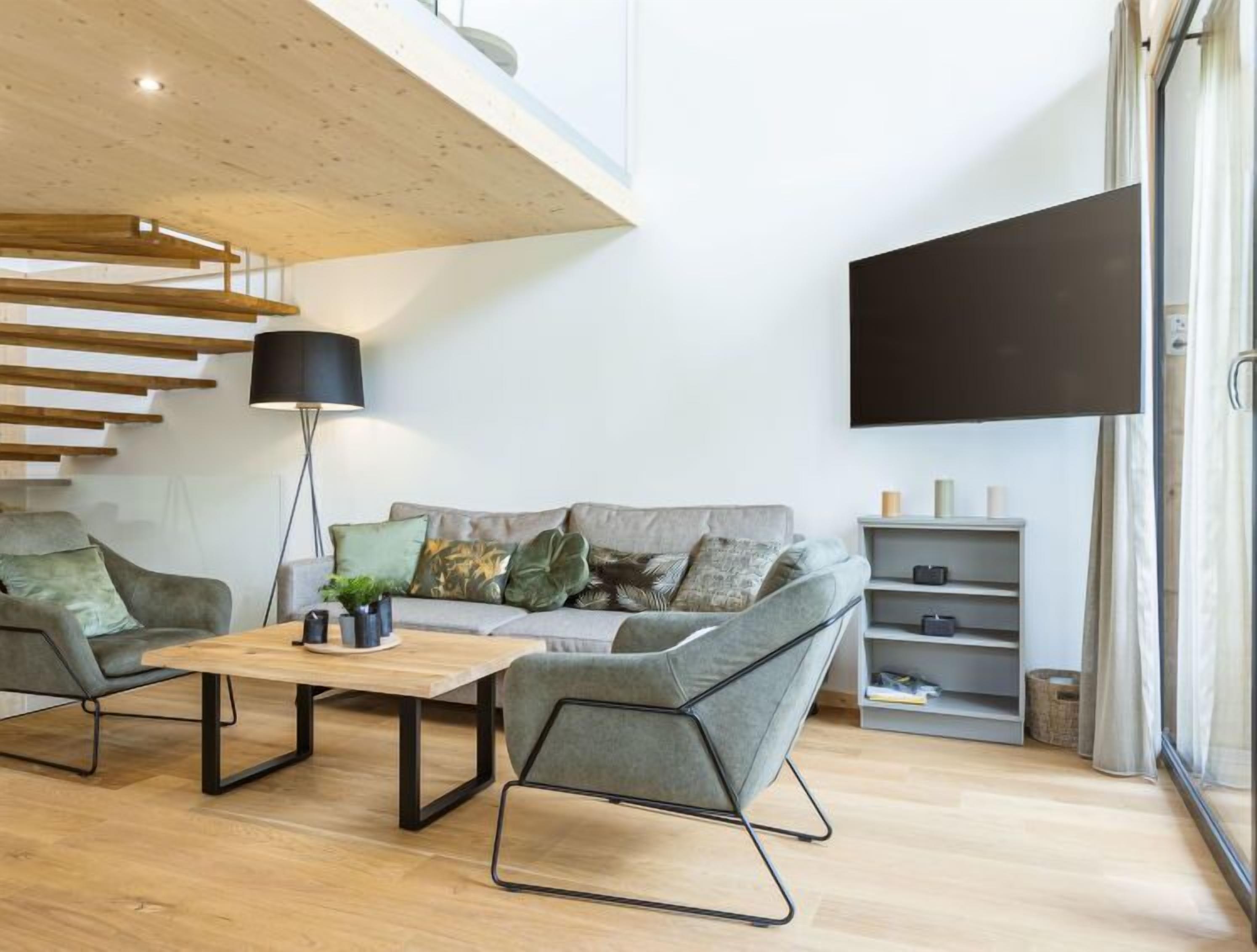 Una sala de estar moderna con techo de madera, un juego de sofá, una mesa de centro y un televisor montado en la pared.