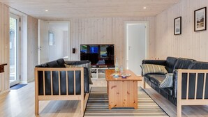Una sala de estar moderna con dos sofás de cuero negro, una mesa de centro de madera y un televisor.