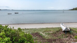 Una masa de agua tranquila con barcos y una playa en primer plano.
