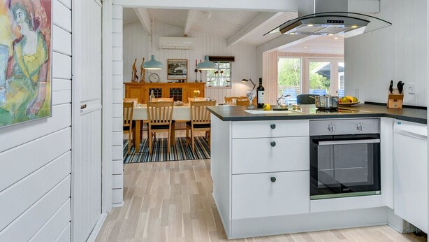 Una cocina moderna con armarios blancos, una isla grande y un horno empotrado.
