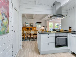 Une cuisine moderne avec des meubles blancs, un grand îlot central et un four encastré.