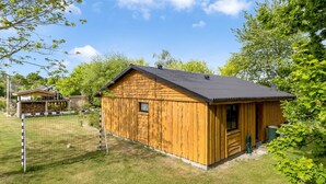Una cabaña de madera con patio cercado y portería de fútbol.
