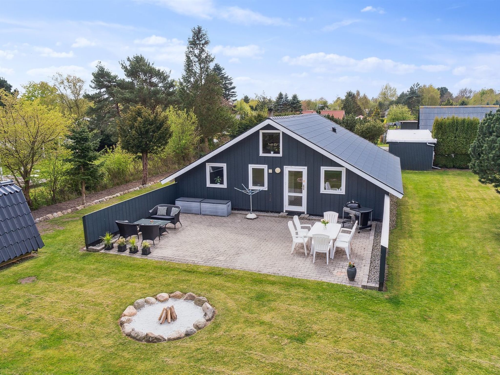 Une maison moderne dotée d’un patio, d’un espace salon extérieur et d’un foyer.