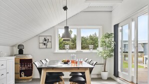 Et moderne køkken med spiseplads, der har et stort vindue, en potteplante og et træskab med glas.