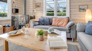 Een gezellige woonkamer met een open haard, houten wanden en een comfortabele bank.