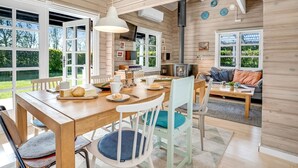 Een ruime, lichtrijke houten hut met een eethoek, keuken en woonruimte.