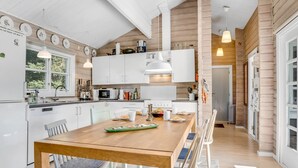 Een moderne keuken met witte kasten, een houten eettafel en hanglampen.