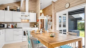 Een moderne keuken met witte kasten, een houten eettafel en een groot raam.