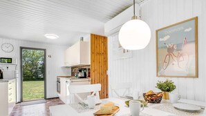 Et moderne køkken med hvide skabe, en trævæg og et spiseområde med et bord dækket til to.