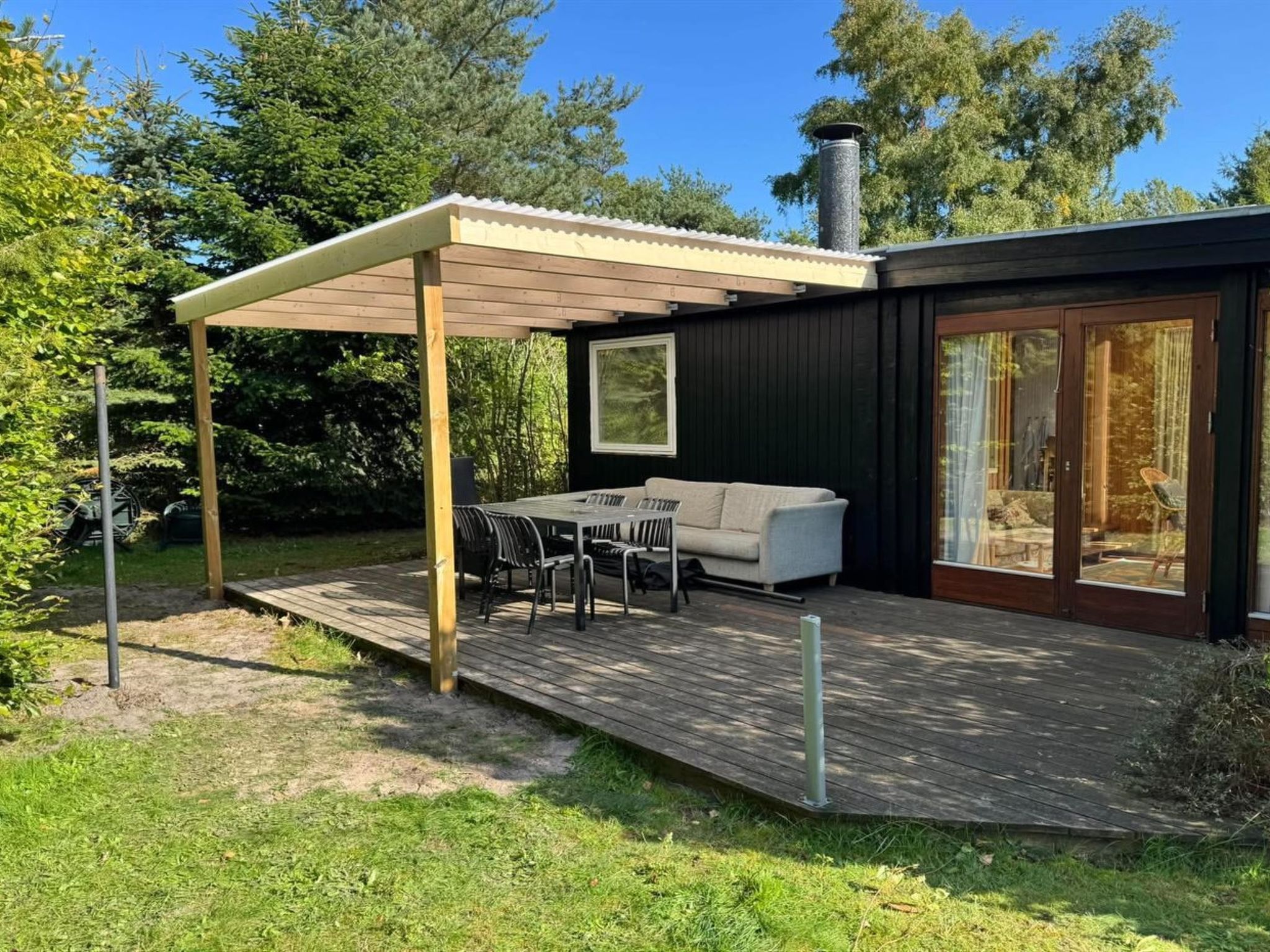 Une terrasse extérieure moderne, dotée d’une table et de chaises, d’un canapé et d’un espace salon abrité.